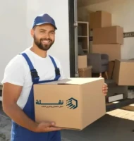 عامل نقل عفش بالرياض يحمل صندوقًا أمام سيارة نقلة